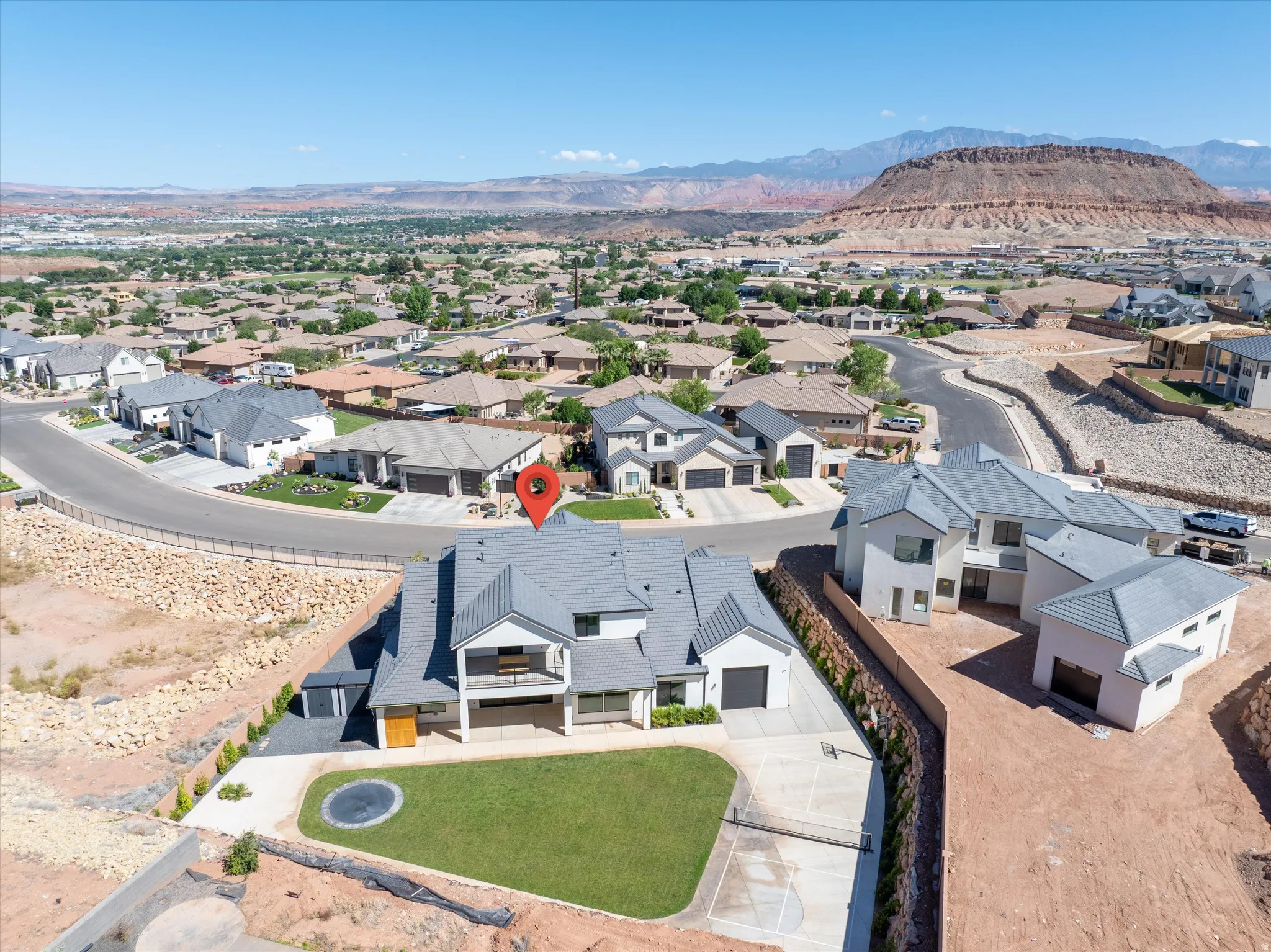 Modern residence with a light gray exterior, a dark gray tile roof, a second-story balcony, a manicured lawn, and a paved driveway