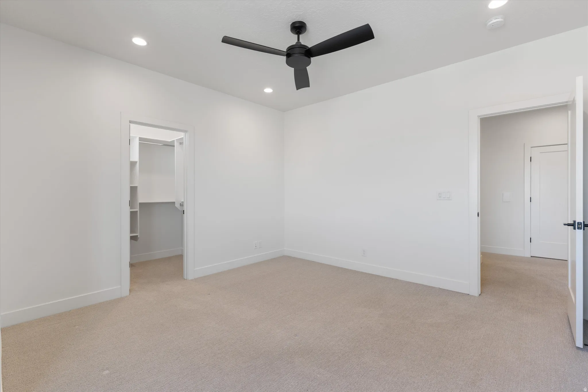 Recessed lighting, ceiling fan, walk-in closet with built-in shelving, white walls, and neutral carpet
