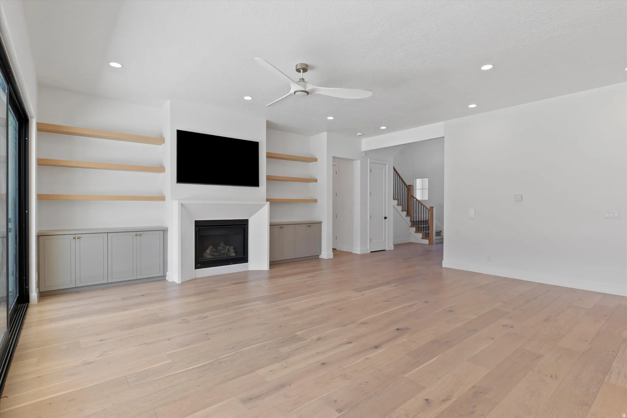 Expansive open room featuring wood-finish flooring, recessed lighting, and a ceiling fan