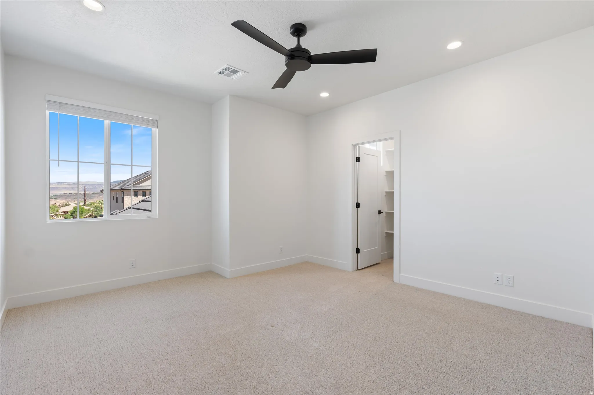Neutral-toned carpet flooring, recessed ceiling lighting, a contemporary ceiling fan, and a walk-in closet with built-in shelving