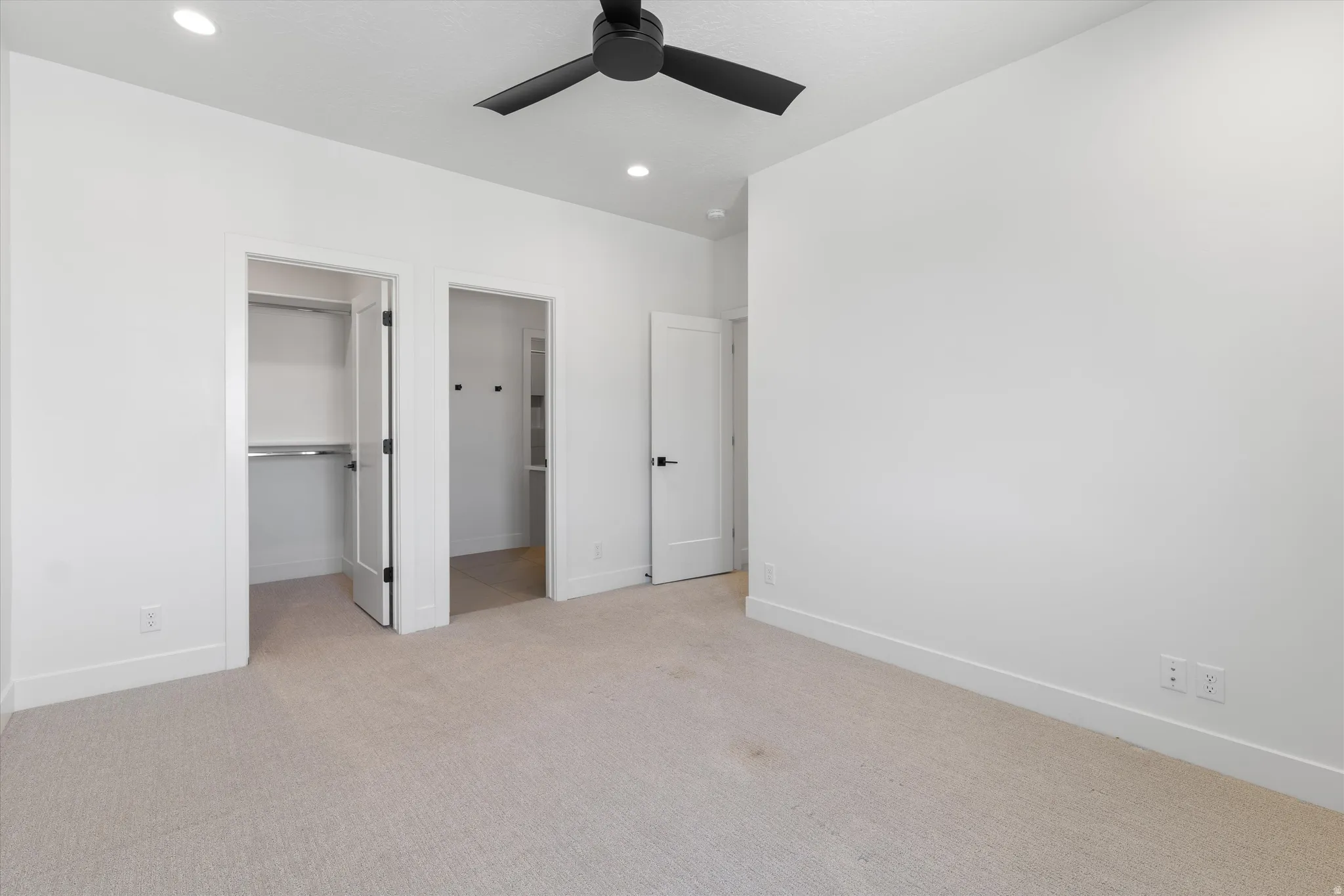 Recessed lighting, ceiling fan with black blades, and light-toned carpet flooring