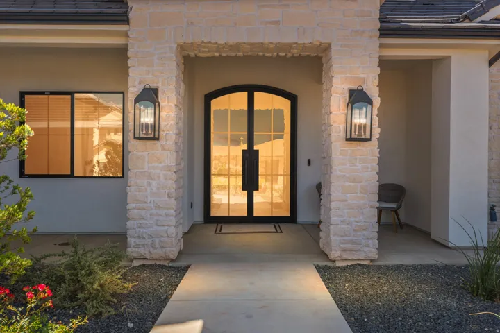 Stone veneer columns frame the arched double entry doors, featuring black metal detailing and transom windows