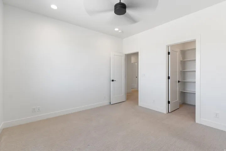 Recessed lighting, ceiling fan, plush carpeting, built-in shelving, and contemporary hardware