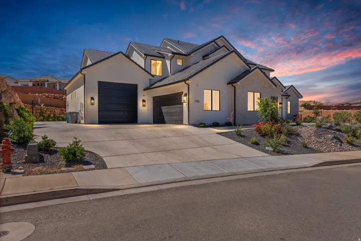 Contemporary exterior architecture with a multi-gabled roof, stone façade accents, dual garage doors, and front landscaping