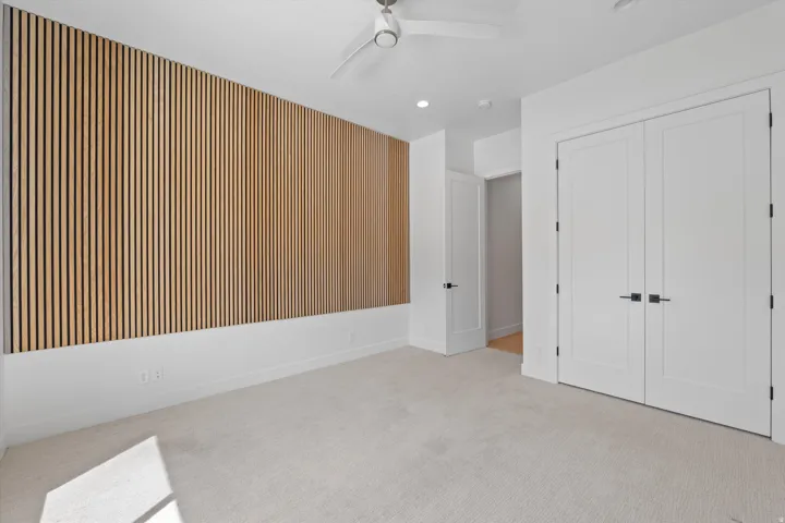 Accent wall with vertical wood paneling, recessed lighting, ceiling fan, and carpeted flooring