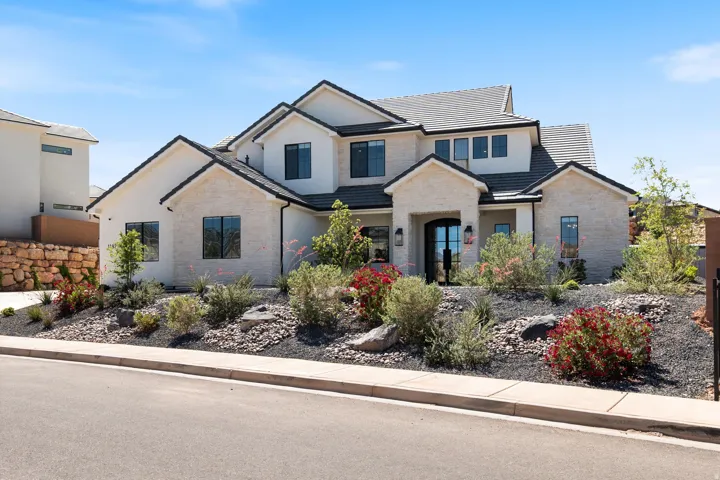 Stucco exterior with stone accents, dark-framed windows, and a dark tile roof