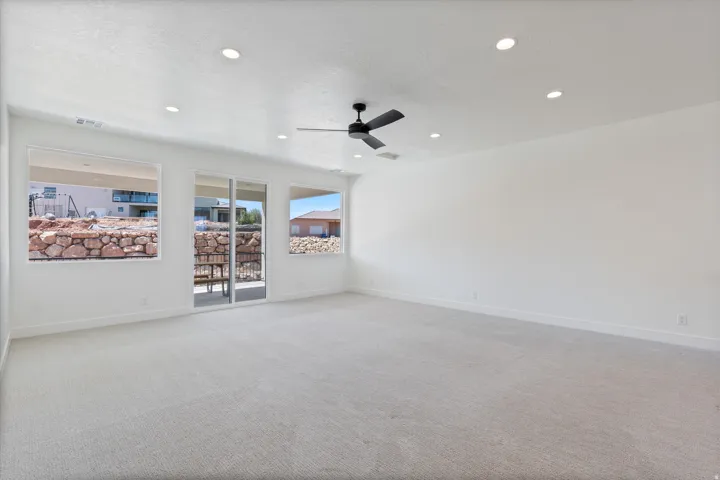 Expansive room featuring light-colored carpeting, recessed lighting, and a ceiling fan