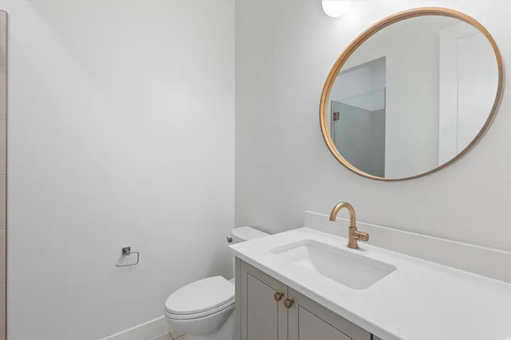 Vanity with integrated sink, gold-finish faucet, and gold-finish round mirror