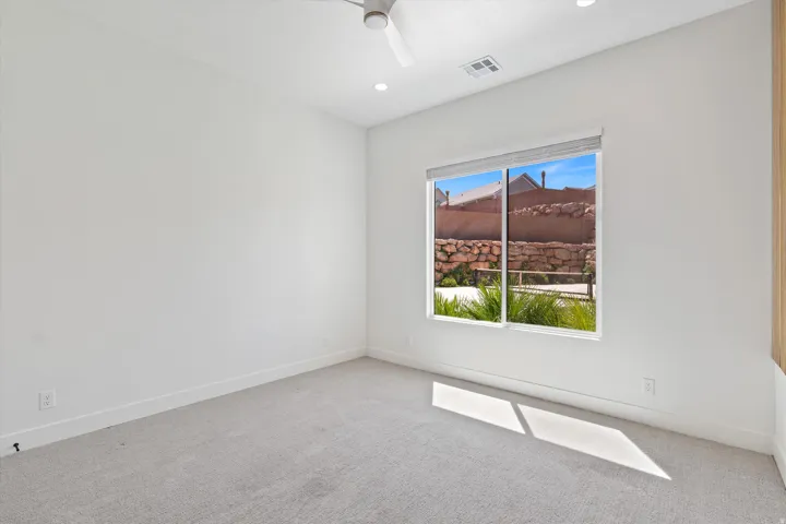 Recessed lighting, ceiling fan, expansive window, light-toned carpet, and neutral wall finishes