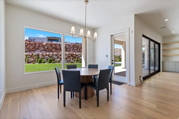 Spacious dining area with wood-finish flooring, a contemporary chandelier, large windows, and direct access to an outdoor area