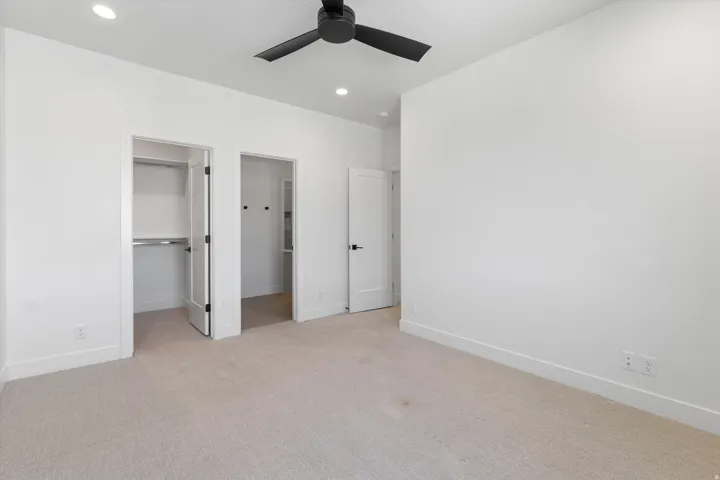 Recessed lighting, ceiling fan with black blades, and light-toned carpet flooring