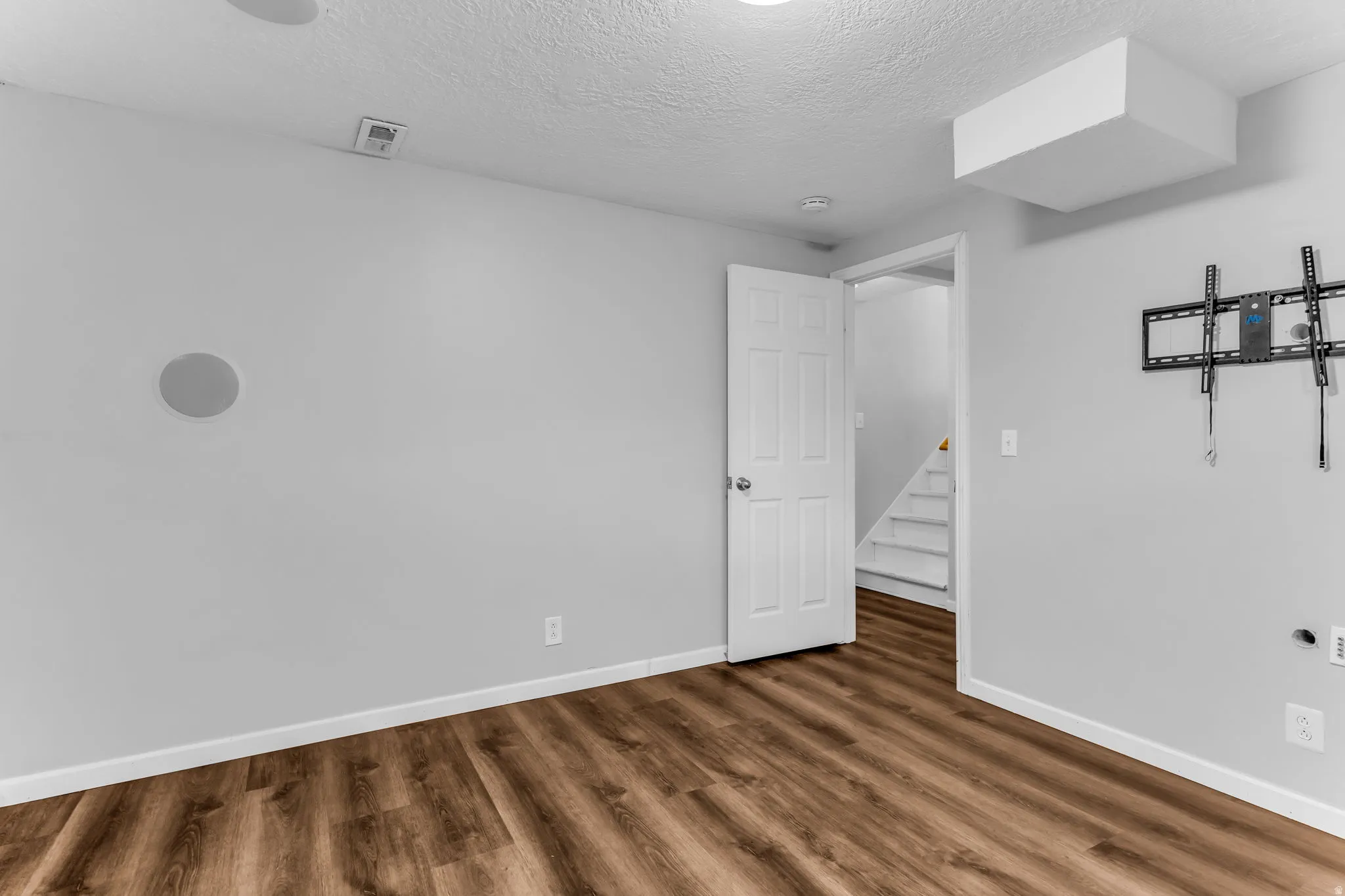 Wood-finish flooring with light gray walls, white trim, and a white paneled door