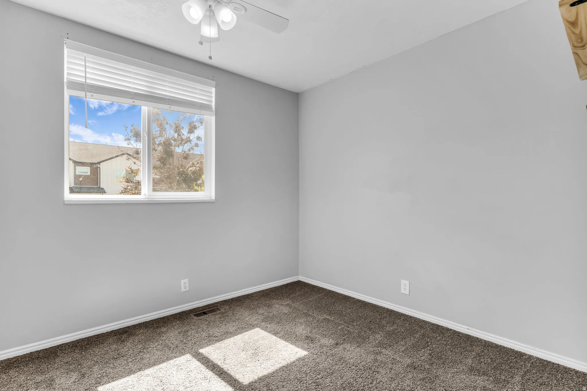 Carpeted room with a window featuring blinds, a ceiling fan with integrated lighting, and light gray walls