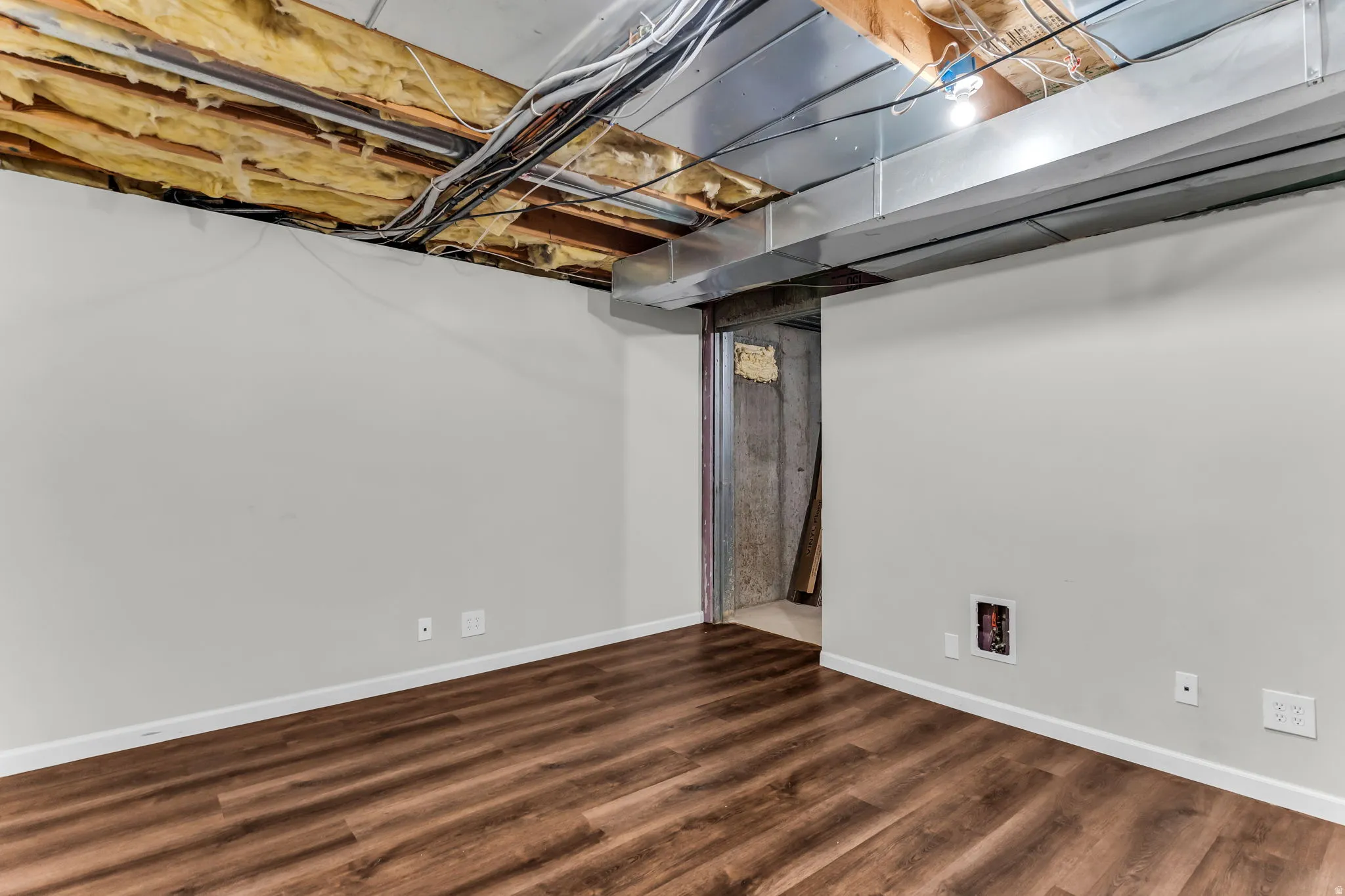 Wood-finish flooring with white baseboards and light grey wall paint