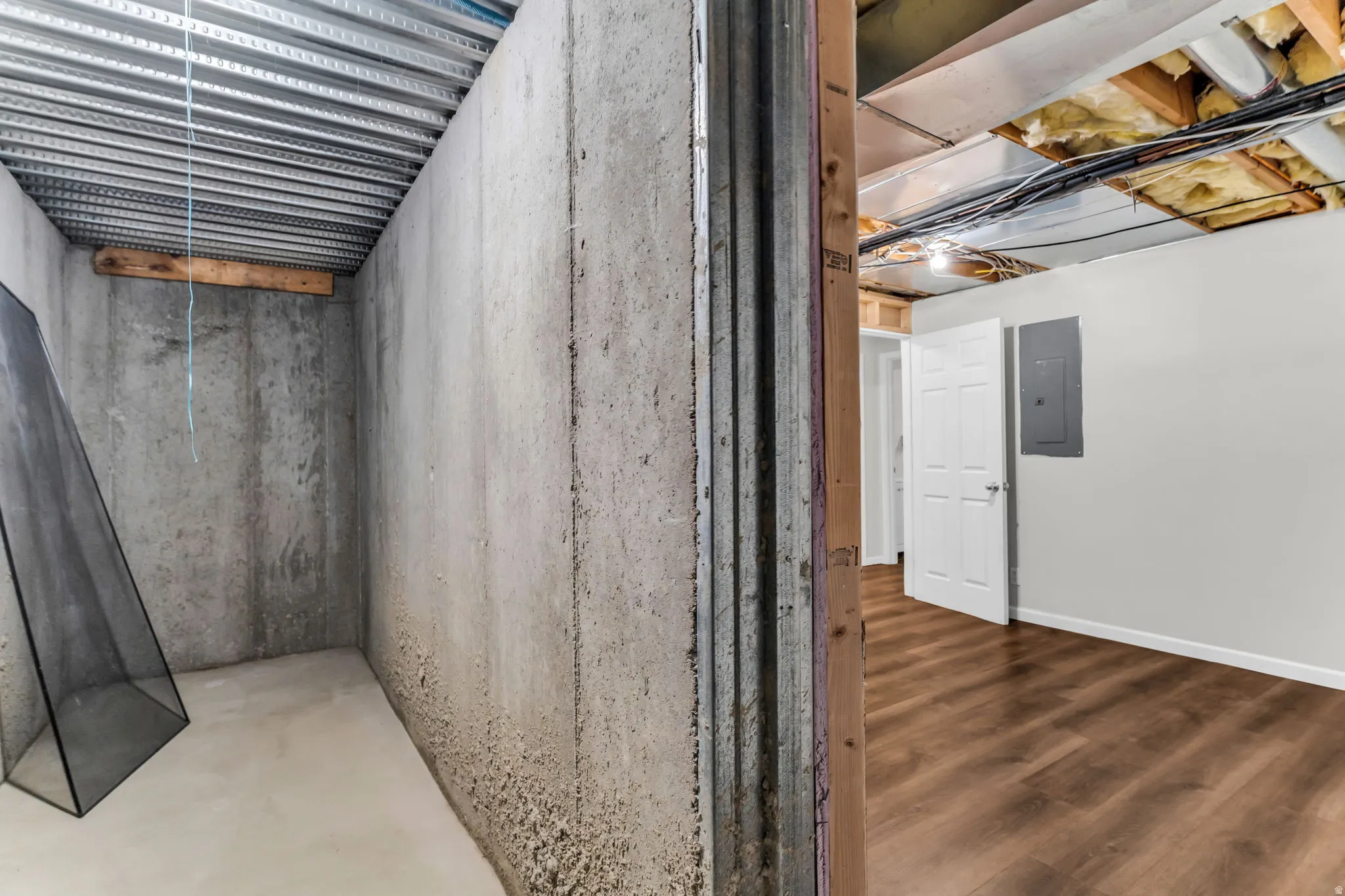 Finished basement area featuring wood-finish flooring, white paneled doors, and painted walls