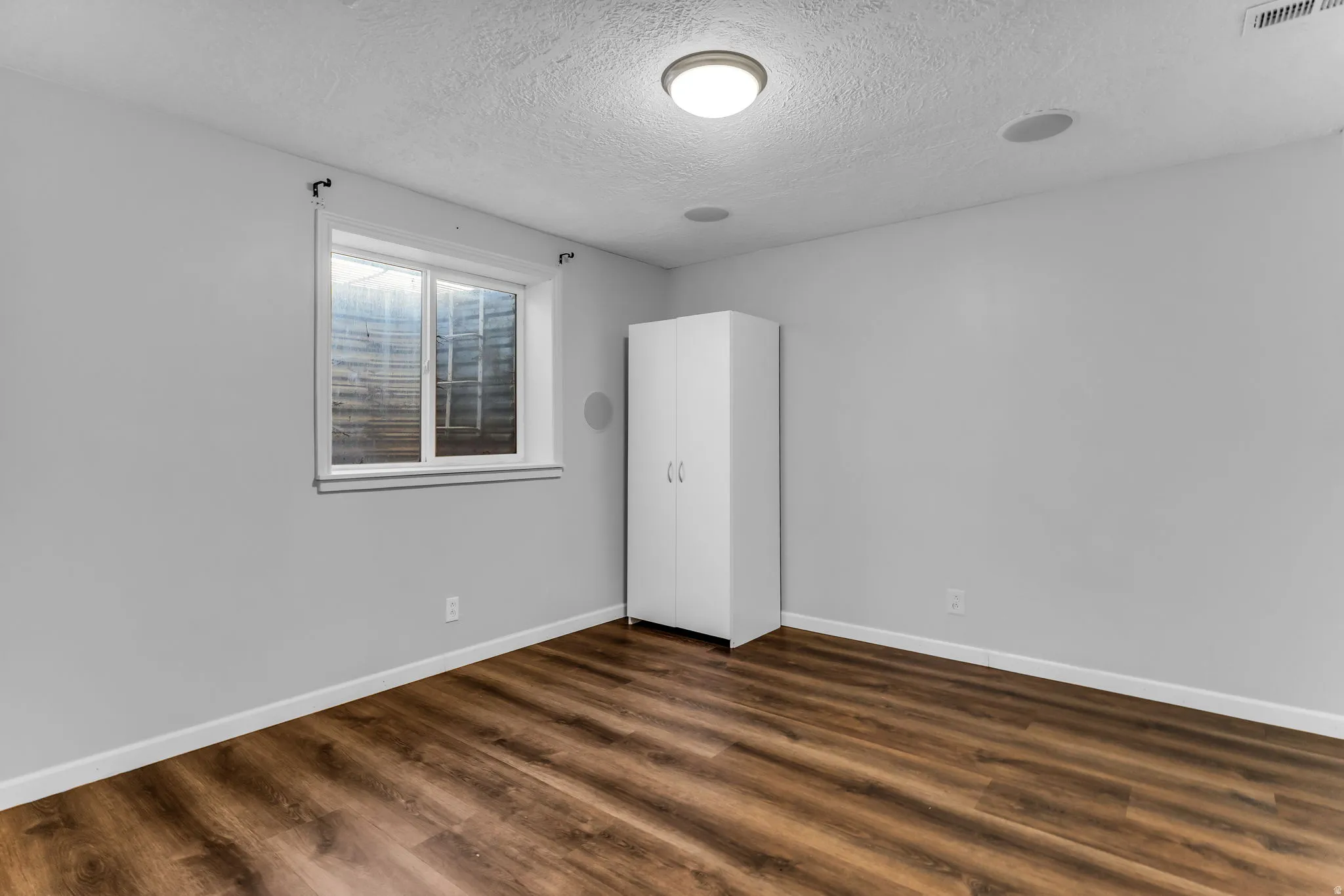 Wood-finish flooring, recessed ceiling lighting, and a single window