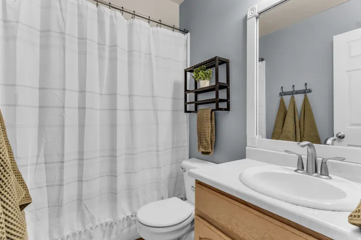 Bathroom featuring a vanity with a white countertop and oval sink, brushed nickel faucet, light wood-finish cabinetry, and a white framed mirror