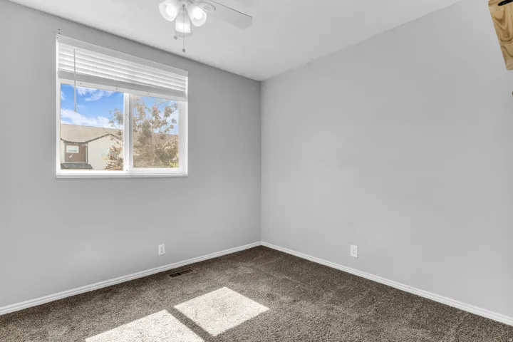 Carpeted room with a window featuring blinds, a ceiling fan with integrated lighting, and light gray walls
