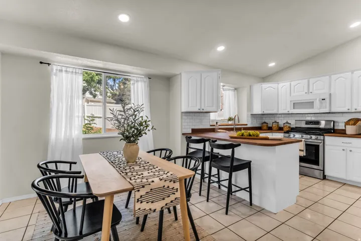 Kitchen featuring white cabinetry, subway tile backsplash, stainless steel appliances, wood-finish countertops, and tile flooring