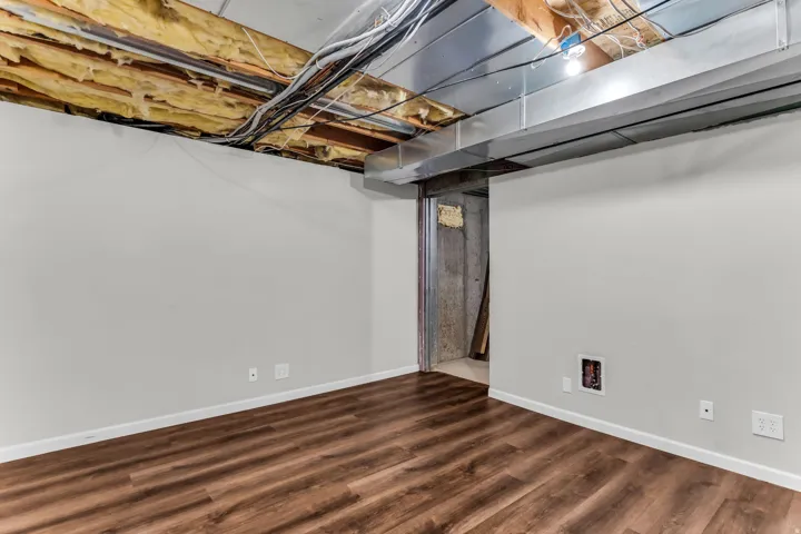 Wood-finish flooring with white baseboards and light grey wall paint