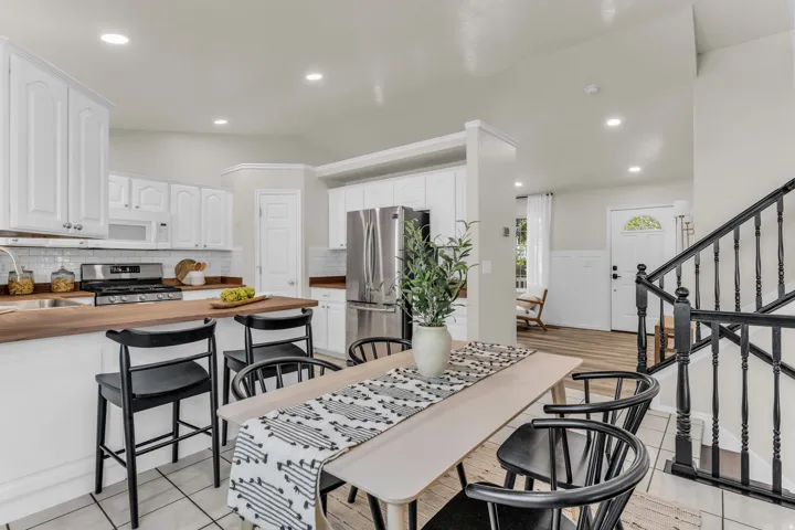 Kitchen featuring white cabinetry, wood-finish countertops, subway tile backsplash, and stainless steel appliances