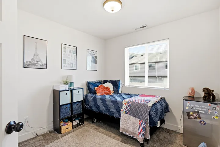 Carpeted room with a ceiling light fixture, white walls, and a window with blinds