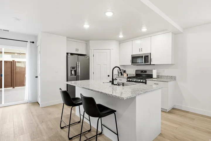 Kitchen featuring a center island, light-toned wood-finish flooring, white cabinetry, stainless steel appliances, and recessed lighting