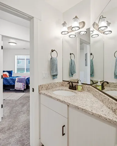Corner vanity with a granite-style countertop, undermount sink, bronze-finish faucet, and coordinating vanity lighting