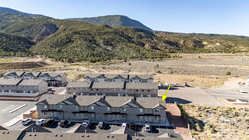 Multi-level townhome with an attached carport, stone accents, and a pitched roofline