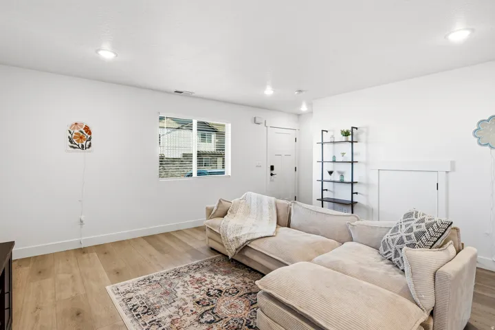 Recessed lighting, wood-finish flooring, white walls, white trim, and a white interior door