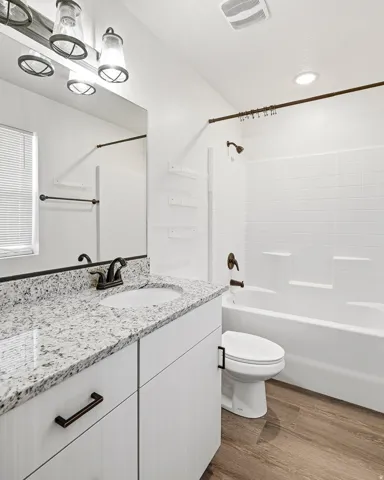 White vanity with a speckled countertop and an undermount sink