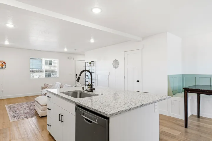 Kitchen island with a light-toned countertop, integrated stainless steel sink, and a matte black faucet