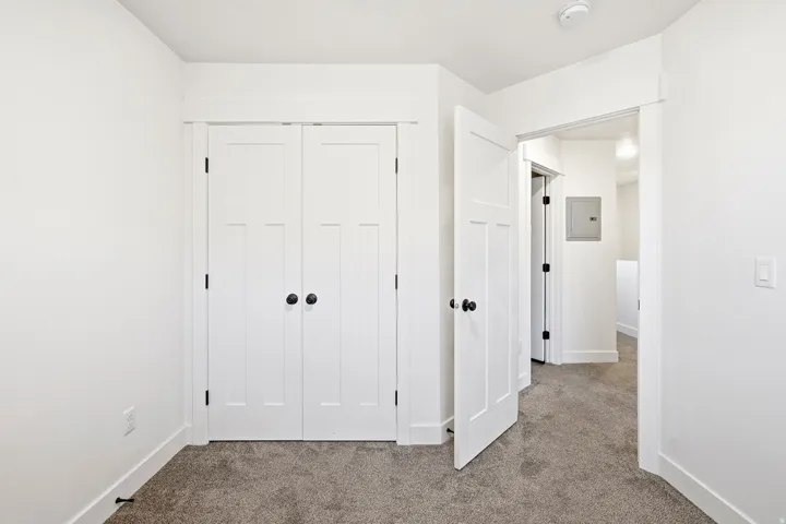White interior doors with black hardware, white trim, and gray carpet