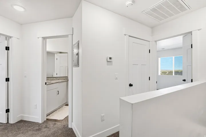 White interior walls, recessed ceiling lighting, three white paneled doors, and gray carpeted flooring