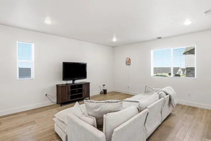 Recessed ceiling lighting, wood-finish flooring, multiple windows with blinds, and white walls