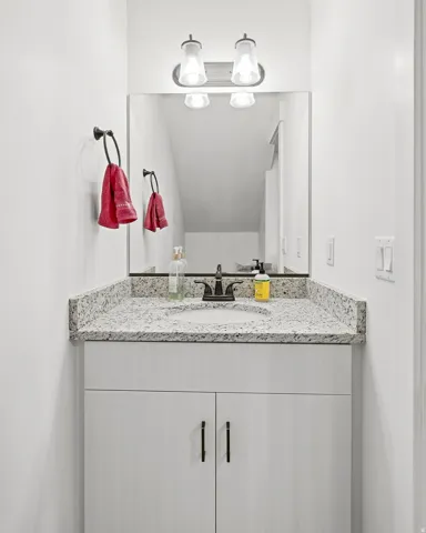 Vanity with a speckled countertop, integrated sink, and dark bronze faucet