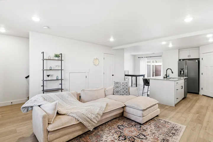 Open-concept living space featuring wood-finish flooring, recessed lighting, and a kitchen island with a dark faucet and stainless steel appliances