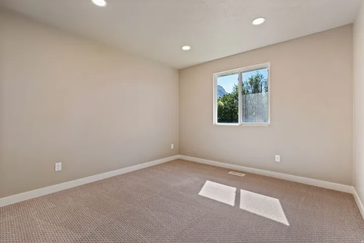 Recessed ceiling lighting, neutral wall paint, carpeted flooring, and a sliding window