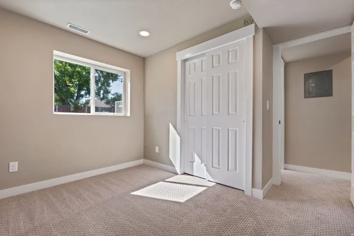 Bright and spacious bedroom featuring dual windows with natural light, neutral wall finishes, neutral carpet flooring, recessed ceiling lighting, and a large closet with six-panel white doors