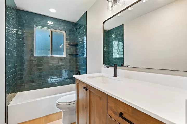 Bathroom featuring a vanity with a white countertop, wood-finish cabinetry, and a rectangular mirror