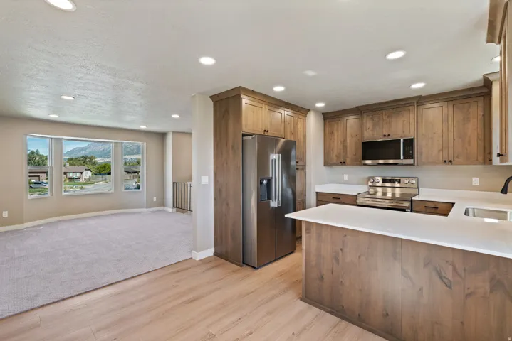 Kitchen with wood-finish cabinetry, stainless steel appliances, and white countertops