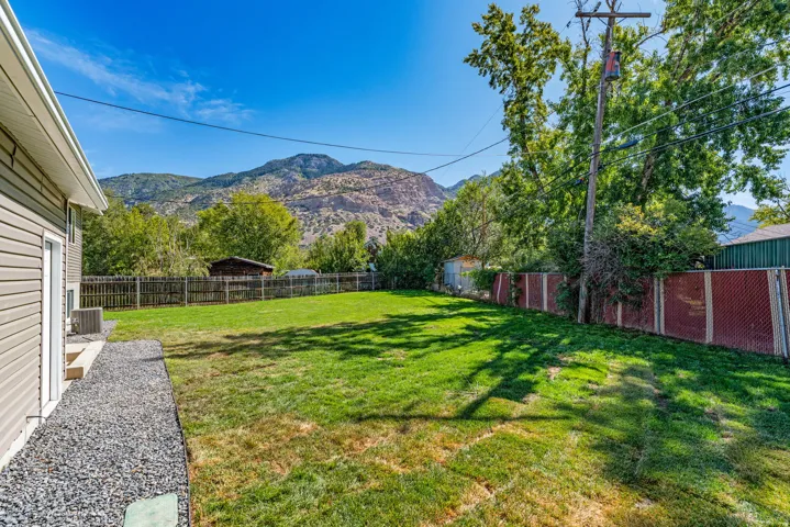Expansive backyard featuring a manicured lawn, established trees, and a wooden privacy fence