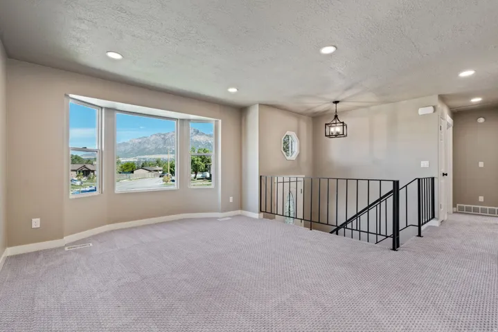 Bay window, recessed ceiling lights, dark iron railing, contemporary chandelier, octagonal window