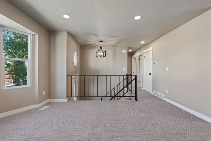 Carpeted area with a bay window, recessed lighting, and a contemporary chandelier