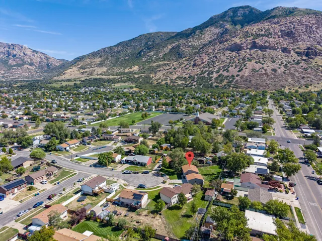 Residential neighborhood with mature trees, mountain backdrop, and clear sky