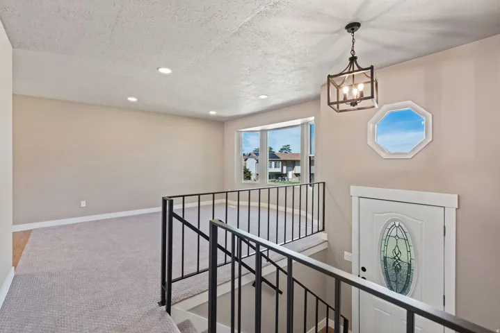 Recessed lighting, bay window, octagon window, decorative front door, and a metal railing staircase