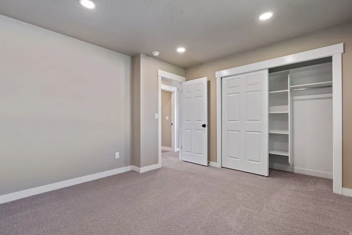 Recessed lighting, neutral wall tones, white trim, and a built-in closet with shelving and hanging rods