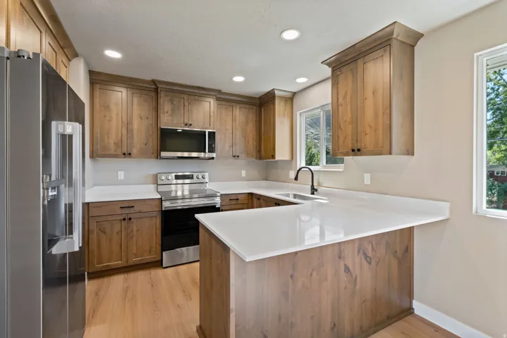 Kitchen featuring wood-finish cabinetry, white countertops, recessed lighting, and stainless steel appliances