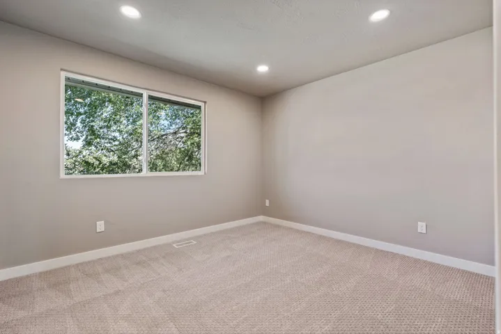 Neutral wall color, recessed ceiling lighting, light-toned carpeting, and a dual-pane window