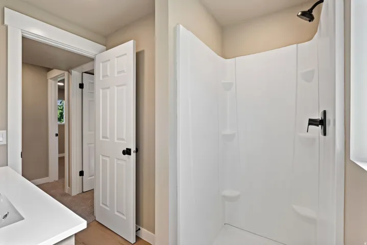 White shower surround with built-in shelving and matte black fixtures
